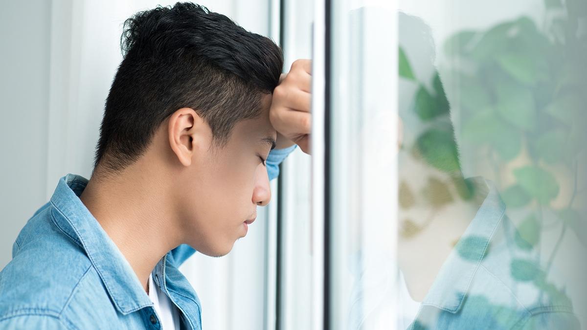 Casual businessman leaning on window looking worried in the office