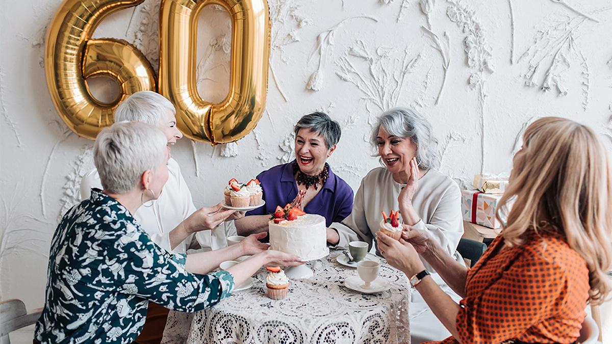 Women celebrating a th birthday with cake.
